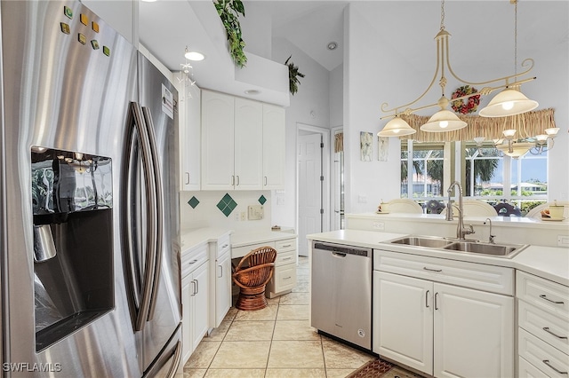 kitchen with stainless steel appliances, sink, white cabinets, hanging light fixtures, and lofted ceiling