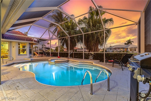 pool at dusk featuring an in ground hot tub, a lanai, a patio area, and a grill