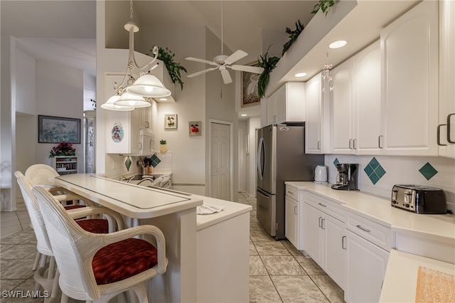 kitchen featuring high vaulted ceiling, a kitchen breakfast bar, ceiling fan, decorative light fixtures, and white cabinetry