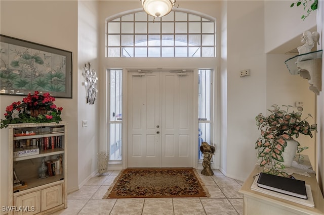 foyer entrance with a high ceiling, light tile patterned floors, and a healthy amount of sunlight