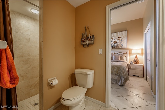 bathroom featuring tile patterned flooring, toilet, and a tile shower