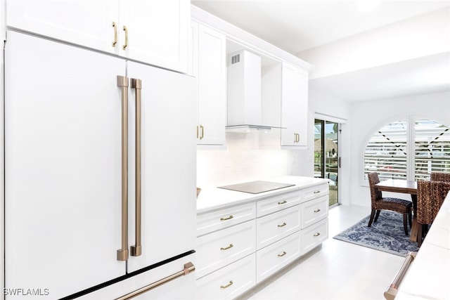 kitchen with black electric cooktop, wall chimney exhaust hood, decorative backsplash, high end fridge, and white cabinets