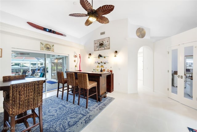 dining space with ceiling fan, vaulted ceiling, bar area, and a healthy amount of sunlight