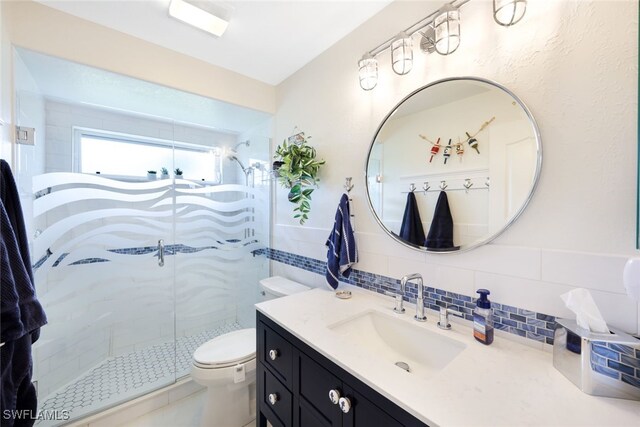 bathroom featuring tasteful backsplash, vanity, tile walls, toilet, and walk in shower