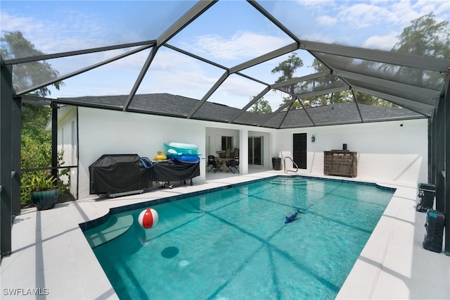 view of pool with area for grilling, glass enclosure, and a patio area