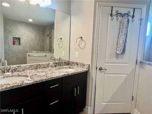 bathroom with a tile shower and vanity