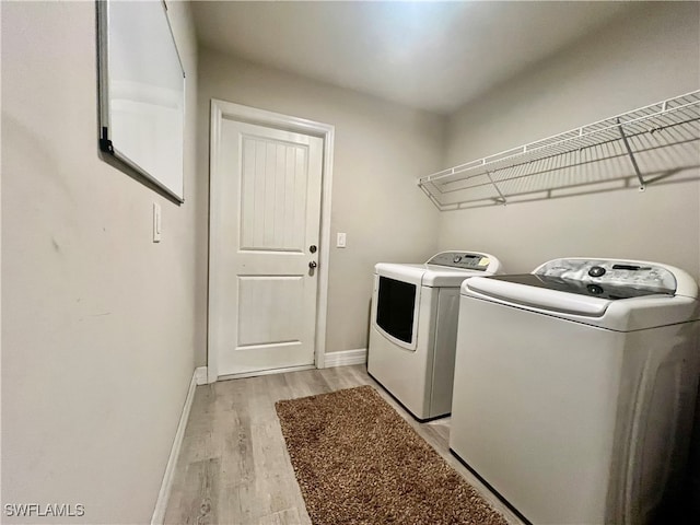 laundry area with washing machine and clothes dryer and light wood-type flooring