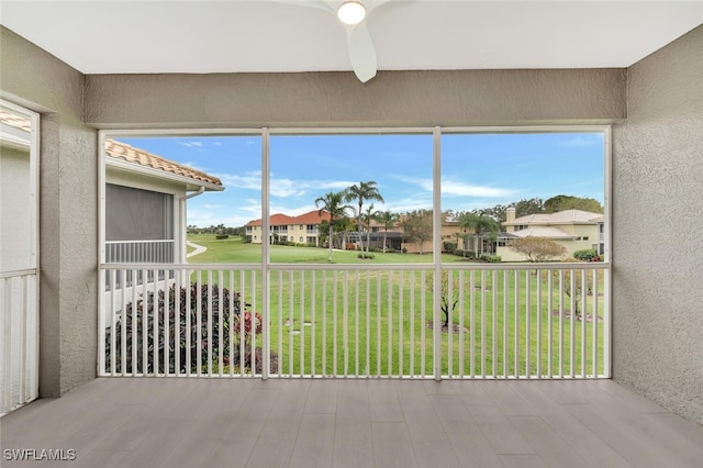 unfurnished sunroom with ceiling fan