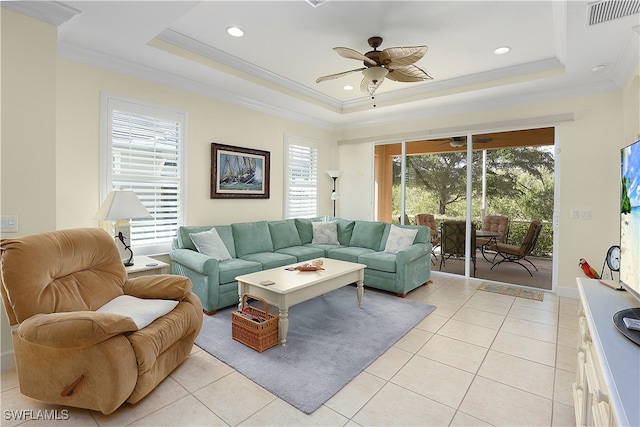 tiled living room with crown molding, ceiling fan, and a raised ceiling