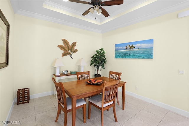 tiled dining space featuring ceiling fan, a tray ceiling, and ornamental molding