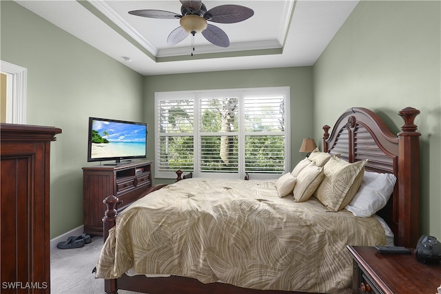 carpeted bedroom with ornamental molding, ceiling fan, and a raised ceiling