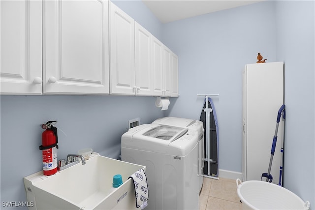 clothes washing area with light tile patterned floors, cabinets, sink, and washer and clothes dryer