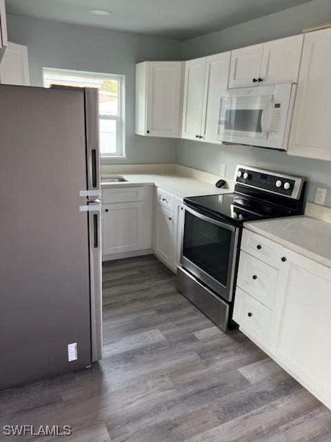 kitchen featuring light hardwood / wood-style floors, white cabinetry, and appliances with stainless steel finishes