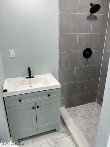 bathroom with a tile shower and vanity