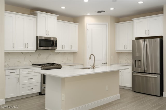 kitchen featuring appliances with stainless steel finishes, light hardwood / wood-style floors, white cabinets, and backsplash