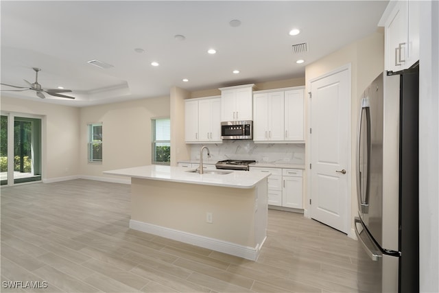 kitchen with appliances with stainless steel finishes, white cabinets, a center island with sink, and a wealth of natural light