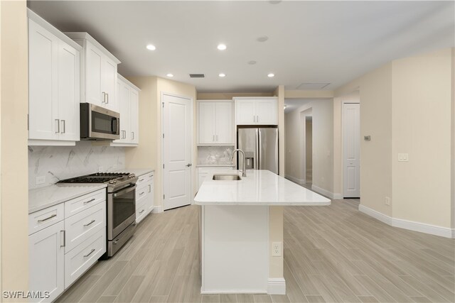 kitchen featuring decorative backsplash, sink, stainless steel appliances, and white cabinets