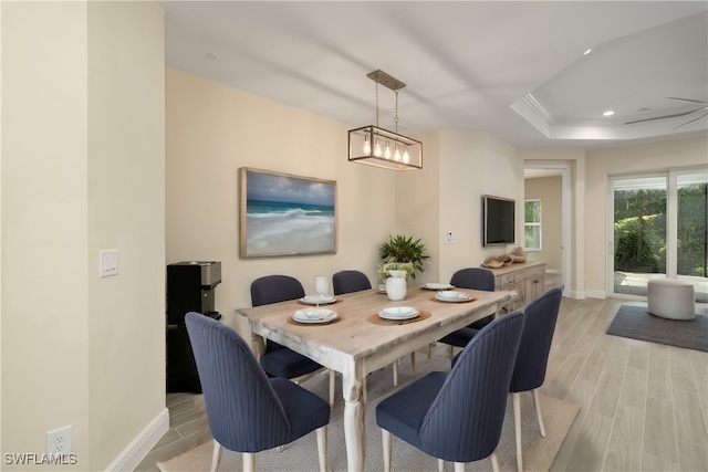 dining area featuring light hardwood / wood-style flooring, an inviting chandelier, and a raised ceiling