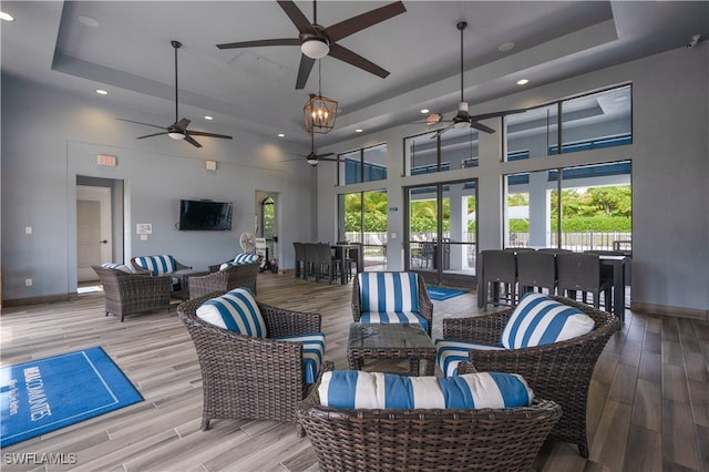 living room featuring a wealth of natural light, a high ceiling, ceiling fan, and a raised ceiling