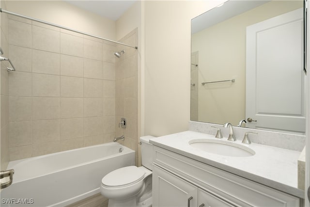 full bathroom featuring vanity, tiled shower / bath combo, and toilet