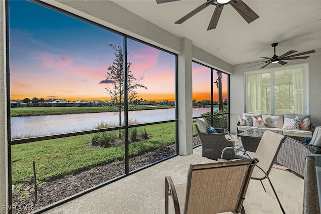 sunroom with ceiling fan and a water view