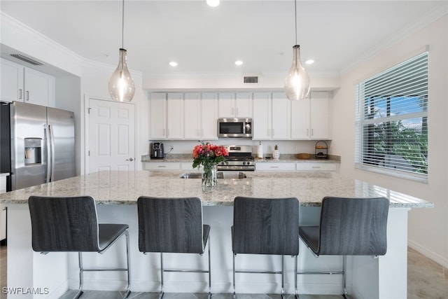 kitchen featuring white cabinetry, appliances with stainless steel finishes, a large island with sink, and hanging light fixtures