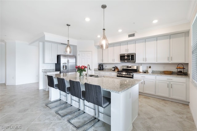 kitchen featuring white cabinets, a center island with sink, appliances with stainless steel finishes, and light stone countertops