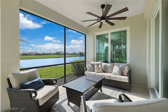 sunroom / solarium featuring ceiling fan and a water view