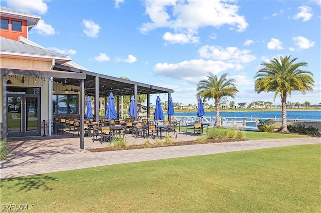 view of community with a yard, a patio, and a water view