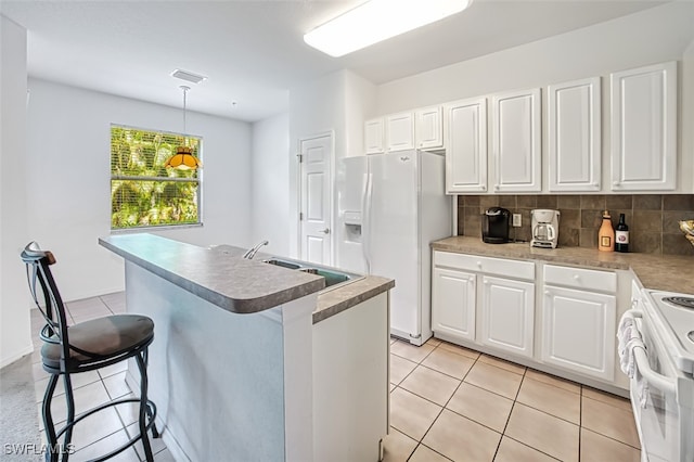 kitchen with pendant lighting, white appliances, white cabinets, and a center island with sink