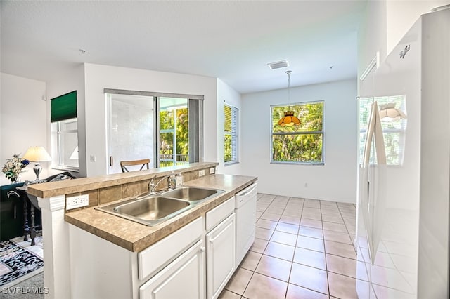 kitchen with decorative light fixtures, white cabinetry, sink, a center island with sink, and white appliances