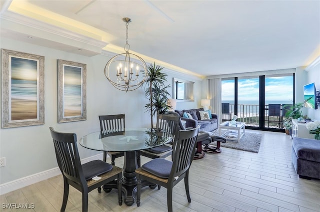 dining space with light hardwood / wood-style flooring, ornamental molding, and an inviting chandelier