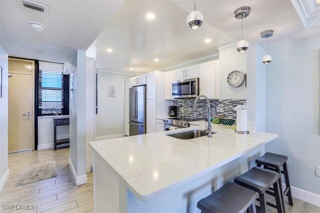 kitchen with tasteful backsplash, stainless steel appliances, white cabinetry, sink, and kitchen peninsula