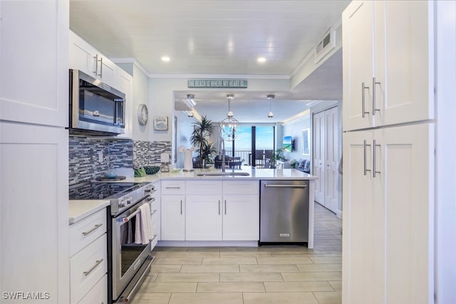 kitchen featuring decorative backsplash, white cabinetry, appliances with stainless steel finishes, kitchen peninsula, and hanging light fixtures