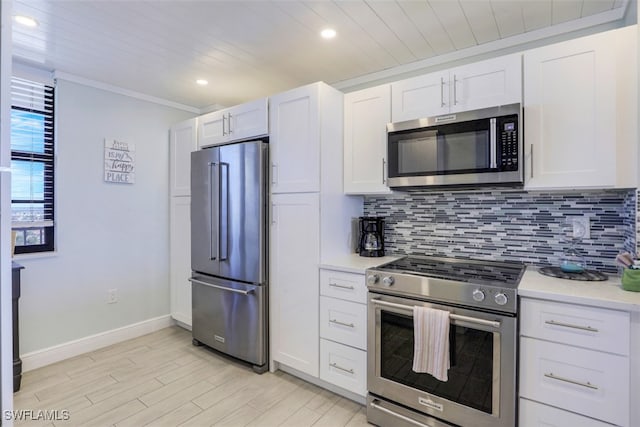 kitchen with decorative backsplash, premium appliances, and white cabinetry