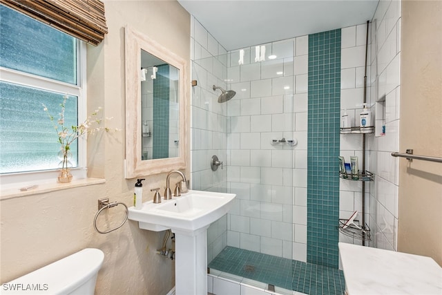 bathroom with a tile shower and toilet