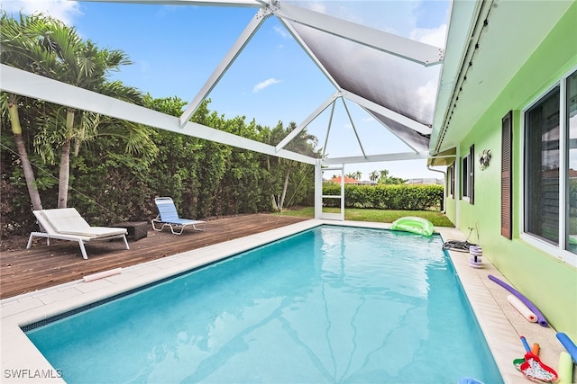 view of swimming pool featuring glass enclosure and a wooden deck