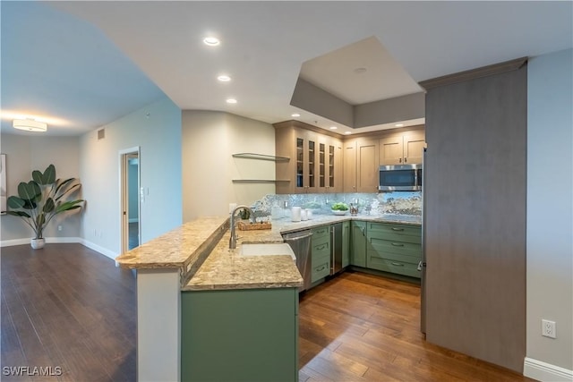 kitchen with a peninsula, dark wood-style flooring, a sink, appliances with stainless steel finishes, and green cabinets