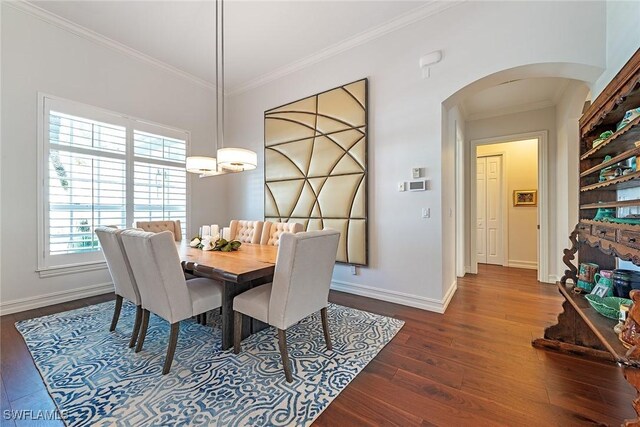 dining area featuring dark wood finished floors, baseboards, arched walkways, and ornamental molding