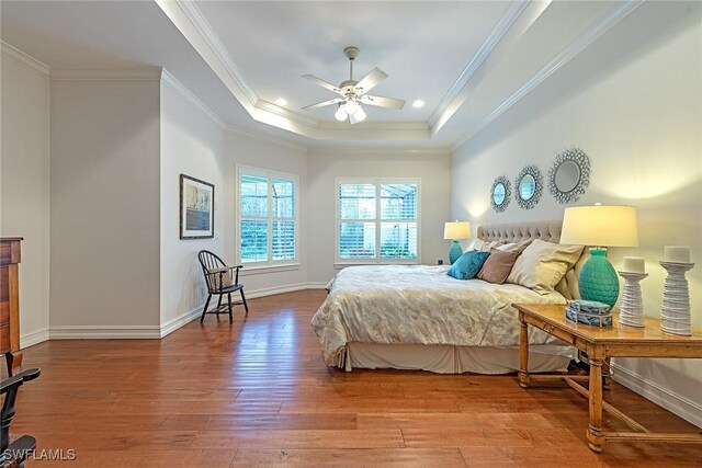 bedroom featuring a raised ceiling, wood finished floors, and ornamental molding