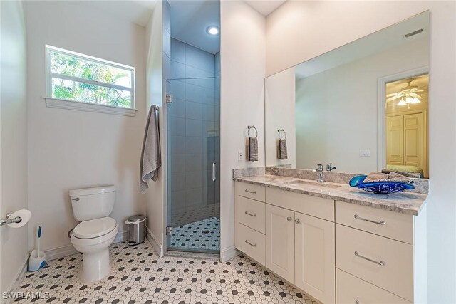 bathroom with tile patterned floors, toilet, a stall shower, baseboards, and vanity