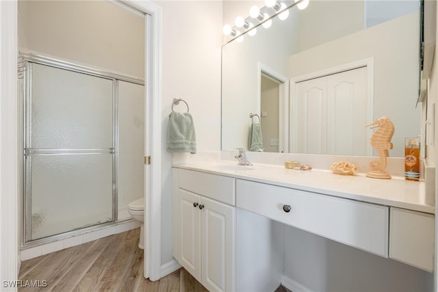 bathroom with a shower with door, toilet, vanity, and wood-type flooring