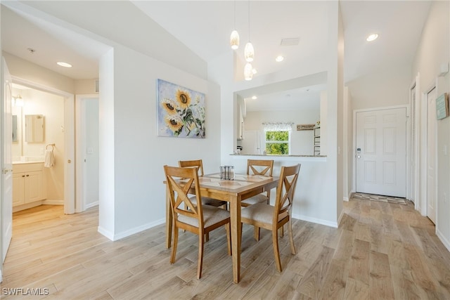 dining space with light hardwood / wood-style flooring and vaulted ceiling