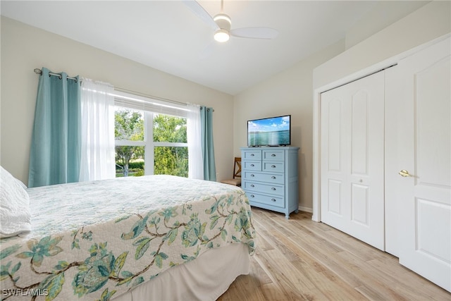 bedroom with light hardwood / wood-style flooring, lofted ceiling, a closet, and ceiling fan