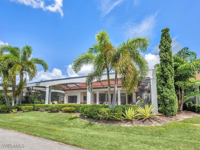 view of front of house with glass enclosure, a front lawn, and stucco siding