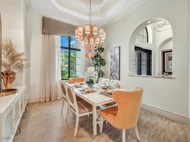 dining room featuring crown molding, a raised ceiling, light wood-style floors, a chandelier, and baseboards