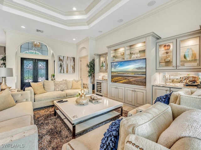 living room featuring visible vents, arched walkways, wine cooler, ornamental molding, and a tray ceiling