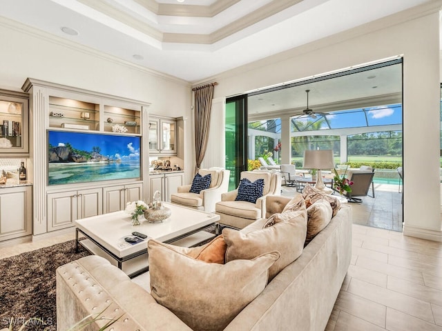 living area with light tile patterned floors, ceiling fan, a sunroom, a raised ceiling, and crown molding