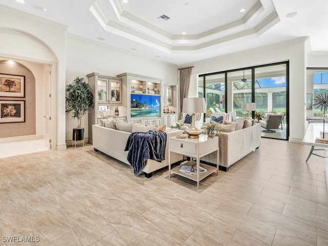 living room featuring baseboards, visible vents, a raised ceiling, and crown molding