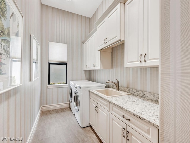 laundry area with a sink, baseboards, washer and dryer, cabinet space, and wallpapered walls